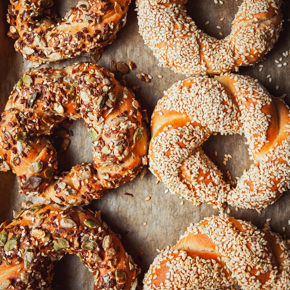 Overhead view of several golden bagels, some topped with sesame seeds, others with mixed seeds.